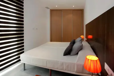 a bedroom with a bed with a wooden headboard and two lamps at Fisa Rentals Les Corts Apartments in Barcelona