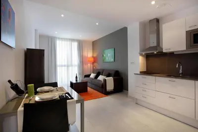 a kitchen and living room with a table and a couch at Fisa Rentals Les Corts Apartments in Barcelona