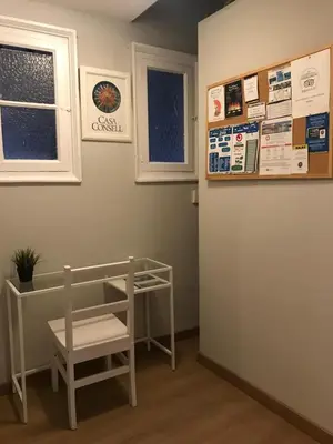 a room with a table and a bench and two windows at Casa Consell Apartments in Barcelona