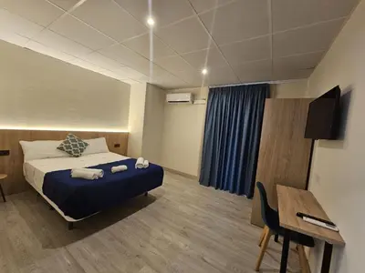 a bedroom with a bed and a table and a desk at Hotel Mar i Sol in Calella