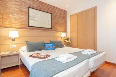 a bedroom with a bed with a laptop on it at Serennia Cest Apartamentos Arc de Triomf in Barcelona