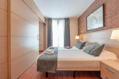 a bedroom with two beds and a brick wall at Serennia Cest Apartamentos Arc de Triomf in Barcelona