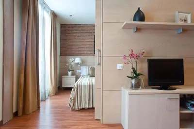 a living room with a television and a bedroom at Serennia Cest Apartamentos Arc de Triomf in Barcelona