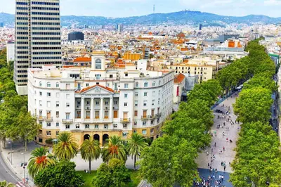 a large white building with palm trees in front of a city at Ikonik Ramblas in Barcelona