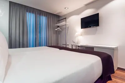 a hotel room with a bed and a flat screen tv at Ikonik Ramblas in Barcelona