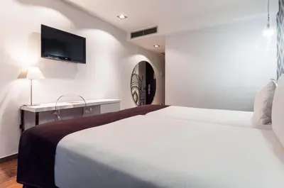 a bedroom with a bed and a desk and a tv at Ikonik Ramblas in Barcelona