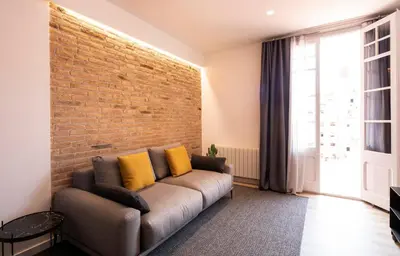 a living room with a couch and a brick wall at Aspasios Sagrada Familia Apartments in Barcelona