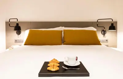 a bed with a tray of donuts and a cup of coffee at Aspasios Sagrada Familia Apartments in Barcelona
