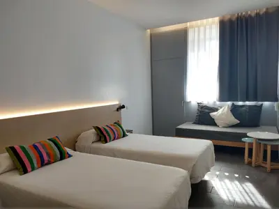 a hotel room with two beds and a couch at Centre Esplai Albergue in El Prat de Llobregat
