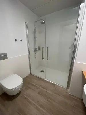 a white bathroom with a shower and a toilet at Centre Esplai Albergue in El Prat de Llobregat