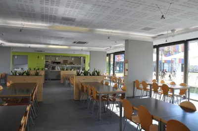 a dining room with tables and chairs and windows at Centre Esplai Albergue in El Prat de Llobregat