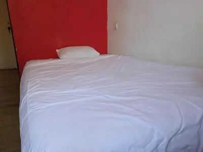 a white bed in a room with a red wall at Pension Casa De Barca in Barcelona