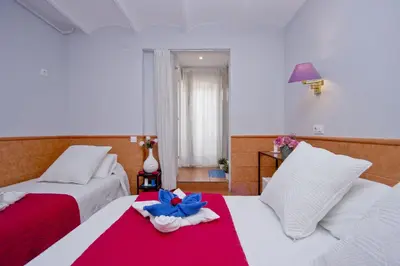a hotel room with two beds with a blue flower on the bed at Barcelona City Rooms Hostal in Barcelona