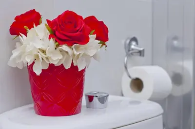 a red vase filled with red and white flowers on a counter at Barcelona City Rooms Hostal in Barcelona
