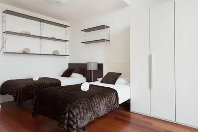 two beds in a room with white walls and wooden floors at Akira Flats Plaza Catalunya Centric apartments in Barcelona