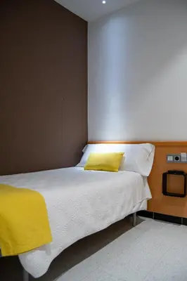 a bedroom with a white bed with a yellow pillow at Hostal Apolo in Barcelona