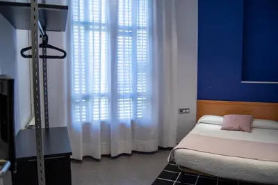 a bedroom with blue walls and a bed and a window at Hostal Apolo in Barcelona