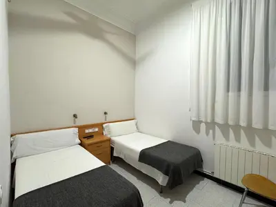 a room with two beds and a window at Pensión Peiró in Barcelona