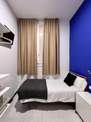 a bedroom with a bed with blue walls and a window at Pensión Peiró in Barcelona