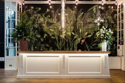 a woman standing behind a counter in a room with plants at Ofelias Hotel 4Sup in Barcelona