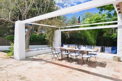 a patio with a table and chairs under a white pergola at Villa Bianca in Sitges