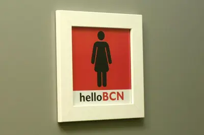a sign on a wall in a bathroom with a woman at HelloBCN Youth Hostel Barcelona in Barcelona