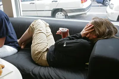 a woman laying on a couch with her head on her face at HelloBCN Youth Hostel Barcelona in Barcelona