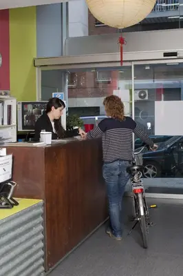 two women standing at a counter in an office with a bike at HelloBCN Youth Hostel Barcelona in Barcelona