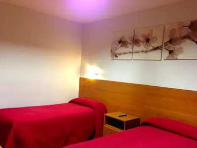a room with two beds and a red bedspread at Hostal Madrazo in Barcelona