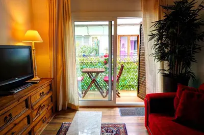 a living room with a tv and a door to a patio at Olivia Apartment by Hello Homes Sitges in Sitges