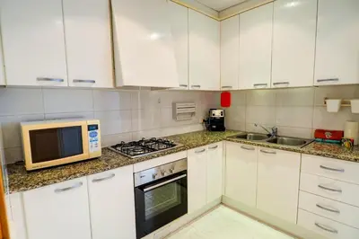a kitchen with white cabinets and a microwave at Lucy Apartment by Hello Homes Sitges in Sitges