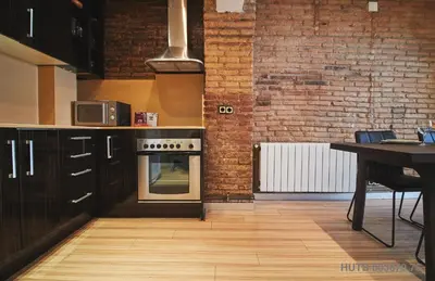 a kitchen with wooden floors and a brick wall at Alcam Alio 1 in Barcelona