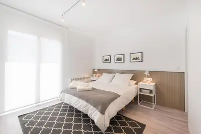 a white bedroom with a bed and a rug at Petit Luxe Dúplex in Terrassa