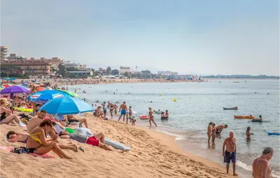 a crowd of people on a beach with umbrellas at Stunning Home In Alella With Wifi in Alella
