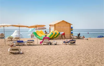 a beach with chairs and umbrellas and people on the beach at Stunning Home In Alella With Wifi in Alella