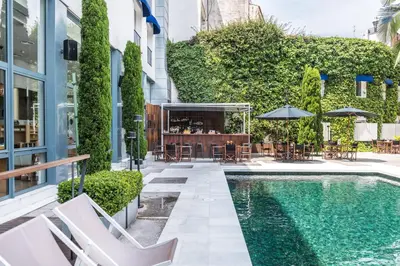 a pool with chairs and a bar next to a building at Hotel Medium Sitges Park in Sitges