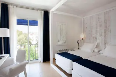 a white bedroom with a bed and a balcony at Hotel Medium Sitges Park in Sitges