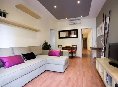 a living room with a white couch and pink pillows at Avinguda Gaudi Apartment in Barcelona