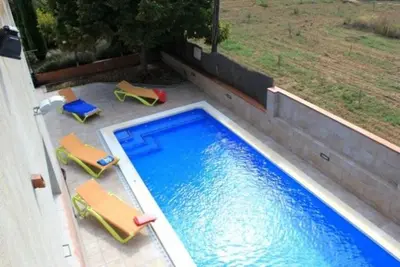 a swimming pool with two lawn chairs next to it at Agroturisme Cal Jeroni in Avinyonet