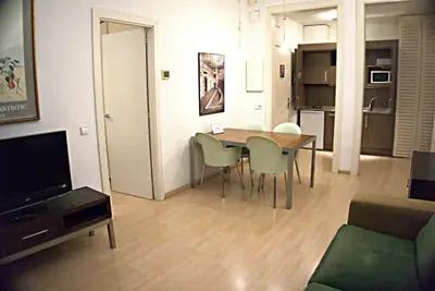 a living room with a table and chairs and a television at Apartaments Sant Jordi Fontanella in Barcelona