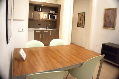 a kitchen with a wooden table and white chairs at Apartaments Sant Jordi Fontanella in Barcelona