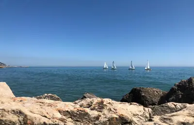 a group of sailboats on the water with rocks at Apartamento Montroig 3 Ático in Sitges