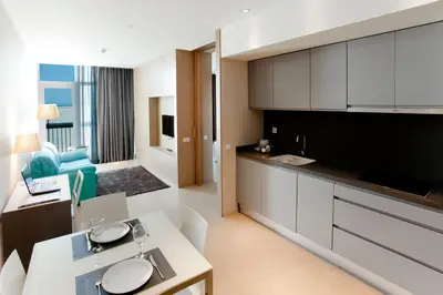 a kitchen with white cabinets and a living room at Atenea Port Barcelona Mataró in Mataró