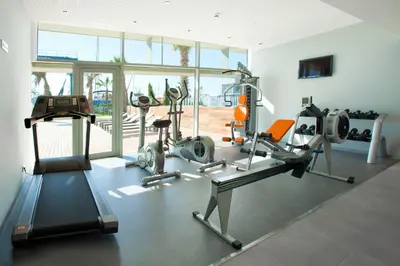 a gym with cardio equipment in a room with windows at Atenea Port Barcelona Mataró in Mataró
