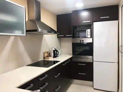 a kitchen with black cabinets and a white refrigerator at Apartamento Montroig 1 in Sitges