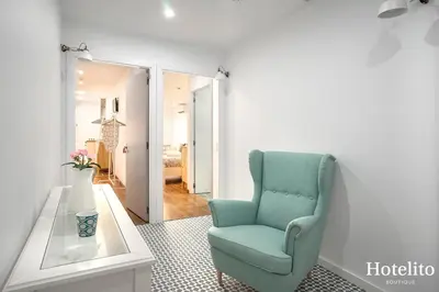 a living room with a blue chair and a table at Hotelito Boutique Mercat in Hospitalet de Llobregat