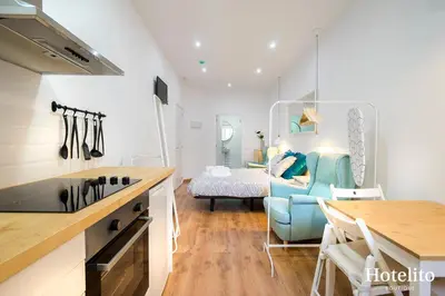 a kitchen and living room with a blue chair and a bed at Hotelito Boutique Mercat in Hospitalet de Llobregat