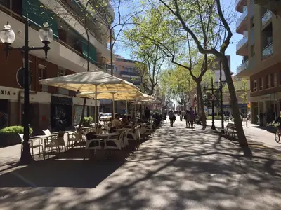 a street with tables and chairs and people walking down the street at Hostal Poblenou in Barcelona