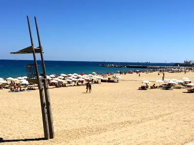 a beach with umbrellas and people on the beach at Hostal Poblenou in Barcelona