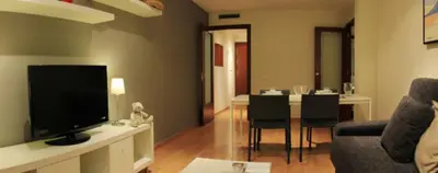 a living room with a television and a dining room at Alguera Apartments Industria in Barcelona